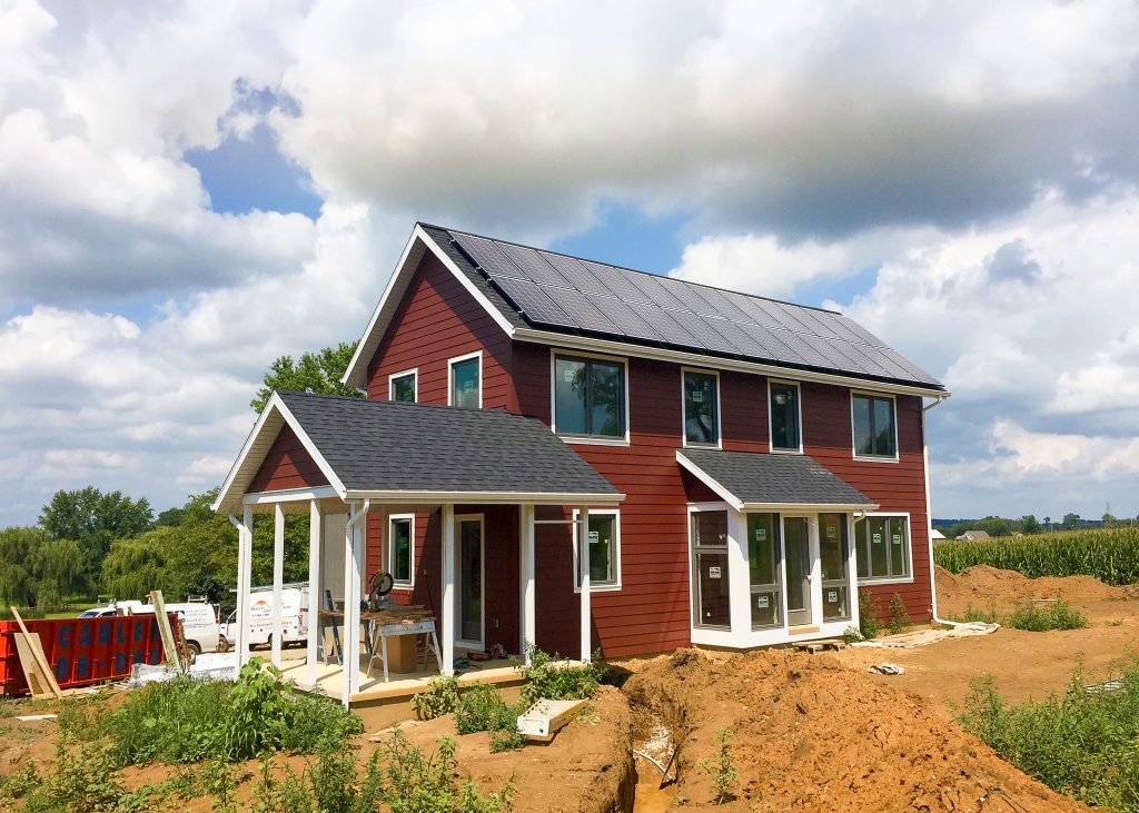 Roof full of solar panels installed on two story home with red siding and white accents - by top solar Installer In Mount Joy PA