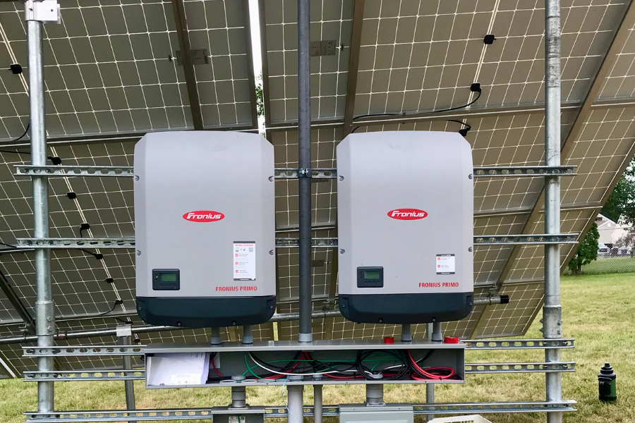 two solar inverters behind ground mount panel